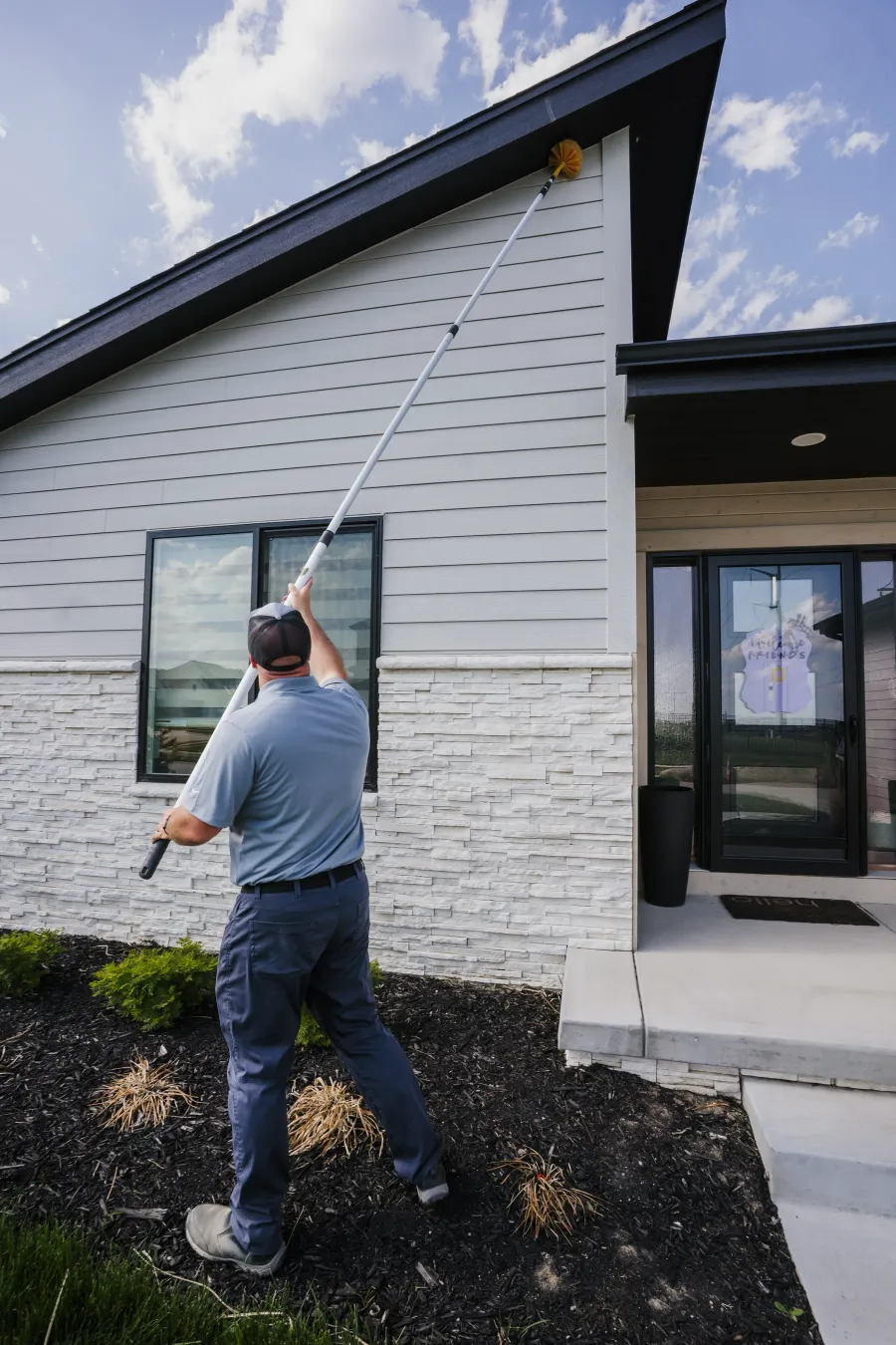 Scott de-webbing the eaves of an Omaha home